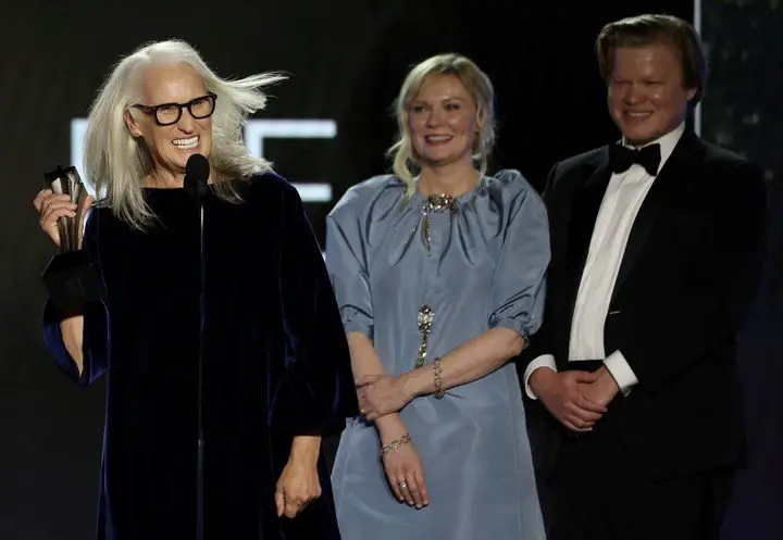 La directora Jane Campion junto a dos de sus actores, Kirsten Dunst y su esposo Jesse Plemons, al recibir el premio a la mejor película. Foto Reuters